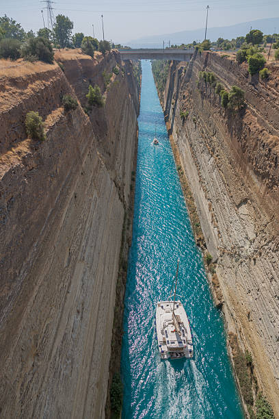 An aerial view of the Corinth Canal, a stunning engineering feat in Greece that connects the Aegean Sea to the Ionian Sea. The canal is characterized by its steep rocky walls and striking turquoise waters, creating a dramatic and picturesque scene. Spanning over 6 kilometers in length and 25 meters wide, the Corinth Canal is a vital maritime route and a remarkable historical landmark. The surrounding greenery and footbridge enhance its scenic beauty, making it an ideal attraction for travelers, history enthusiasts, and nature lovers.