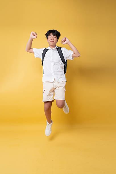 istock Jubilant student leaps with backpack against yellow backdrop radiating youthful energy and spirit 2236372176