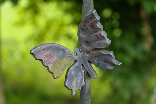A metallic butterfly adorning a metal decorative element symbolizes lightness and grace, contrasting with the strength of the material.
