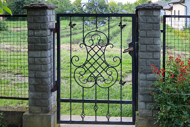 istock A metal gate with wrought-iron patterns between brick pillars creates a feeling of coziness, hospitality, and security. This shot conveys the atmosphere of a rural yard, filling the space with tradition and artistry. 2236373989