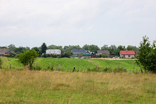 A panoramic view of a small village nestled amid green fields and hills, creating an atmosphere of tranquility and simple life.