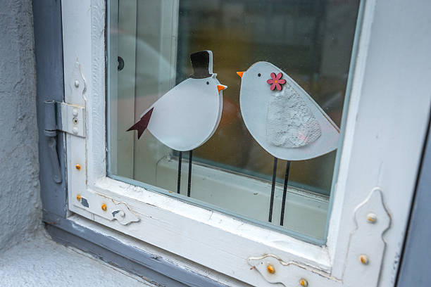 Two decorative birds on a window in historical medieval Lubeck, Schleswig-Holstein, Germany. The window has a windowsill, frame, and decorative hinges, with a winter and christmas atmosphere.