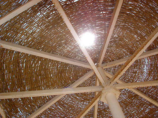 Wicker sunshade with sun flare . Beach umbrella on metal frames