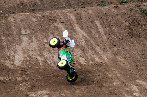 Radio-controlled car performing a backflip on a dirt track