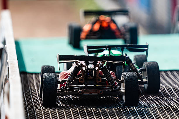 Radio-controlled cars are lined up on a track, awaiting the start of a race, showcasing speed, competition, and hobbyist passion