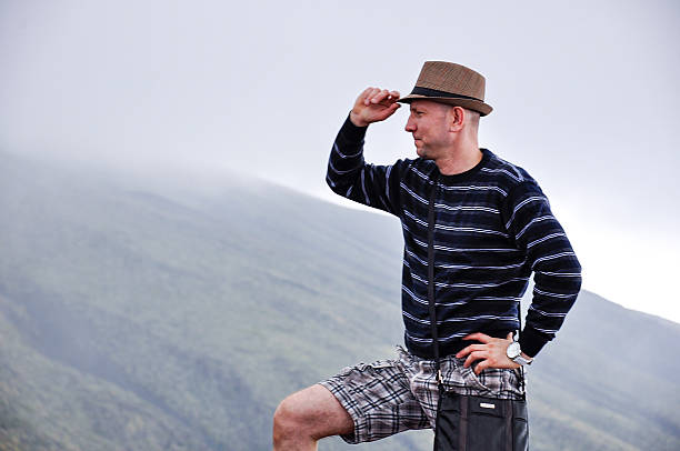 A young Caucasian man on Mount Etna, Sicily, looking into the distance, misty clouds.