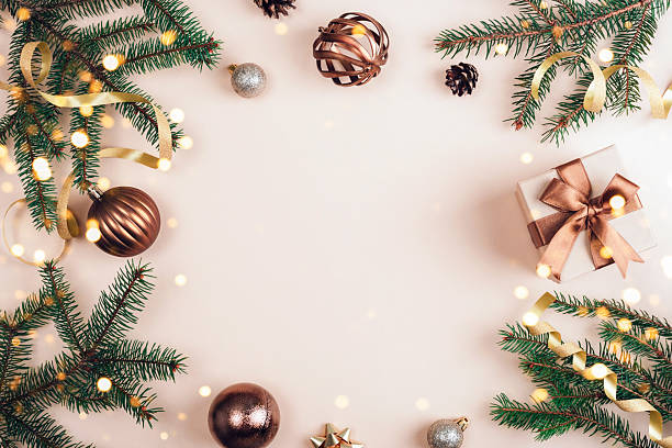 istock Christmas composition with green pine branches, gift box with brown ribbon and ornaments arranged on a beige background. Top view, flat lay, copy space 2236383302