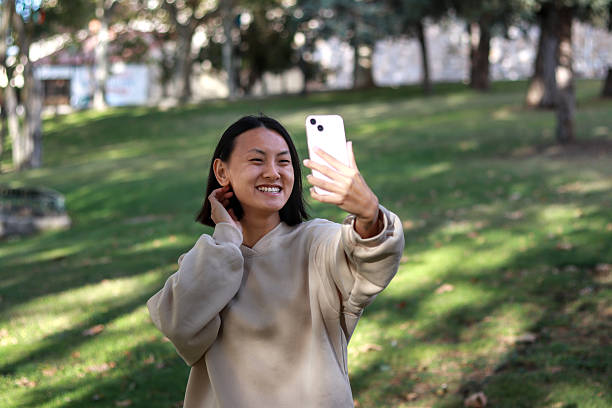 istock Smiling Asian woman taking a selfie in a park 2236389174