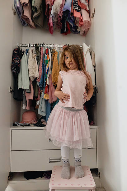 istock Young girl making funny face in closet trying on clothes 2236389964