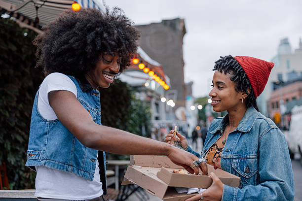 istock Two friends eating pizza on the street 2236393610