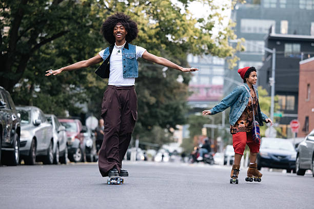 In New York City streets a young couple of friends in hipster style riding on skateboards and roller skates in Williamsburg, Brooklyn.