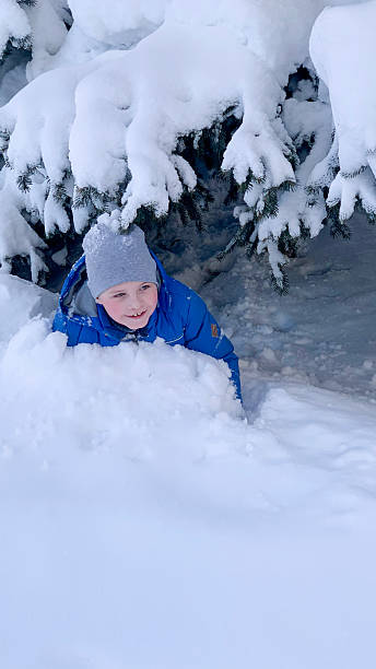 istock A child peeks from beneath a snow-covered tree, surrounded by thick winter snow. 2236393799