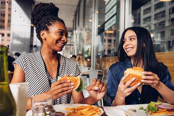 istock Two businesswomen eating hamburger at lunch break 2236393904