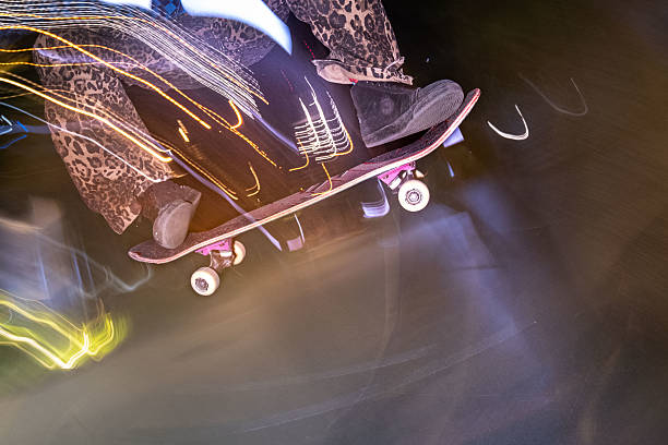 Japanese skateboarder making mid air skateboarding tricks and stunts in front of dark background. Close up and motion blur images