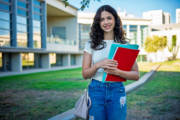 istock Smiling university student holding books on campus 2236396571