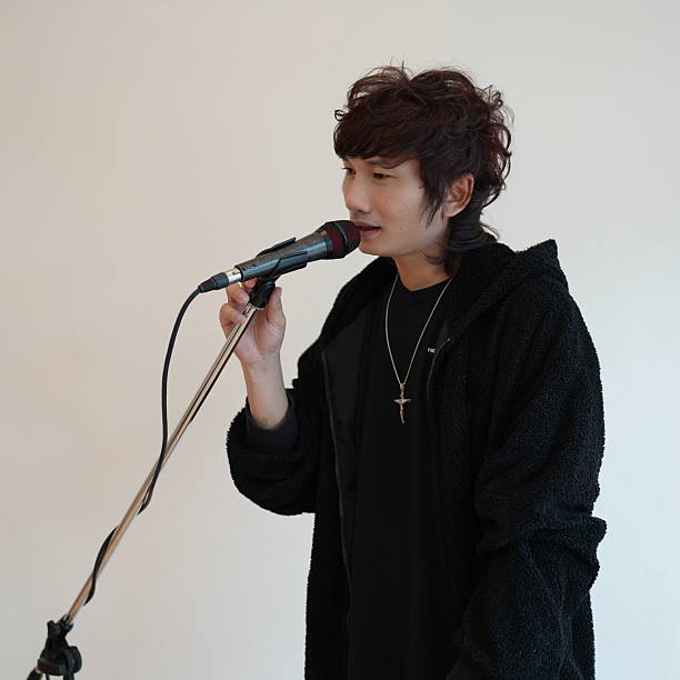 istock Young Male Performing Live Music on Stage with Microphone and Passionate Expression in Minimalist Indoor Setting 2236405977