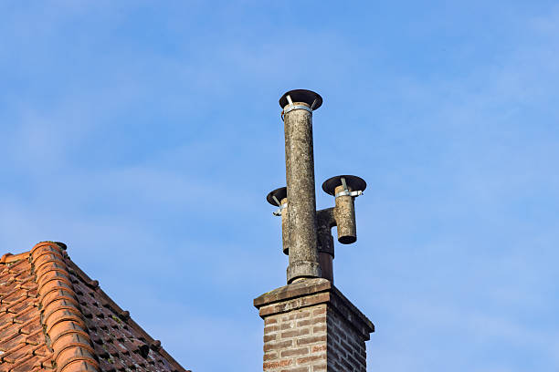 istock An old-fashioned brick chimney with multiple smokestacks on a tiled rooftop 2236406376