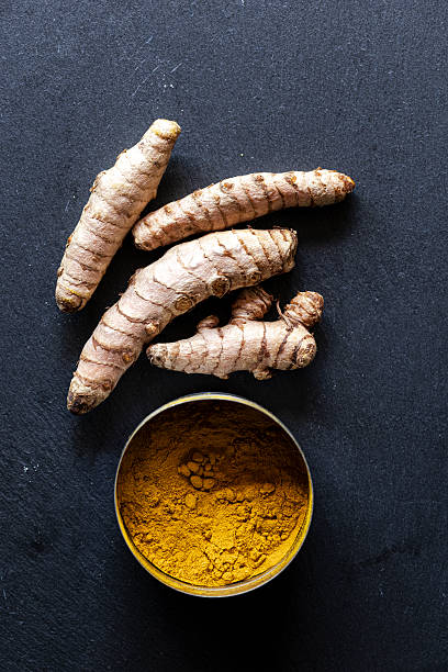 istock Fresh Turmeric Roots and Ground Powder on Dark Slate Background 2236407186