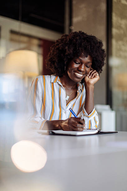 istock Young Professional Woman Smiling While Writing by Hand in a Modern Office 2236408156