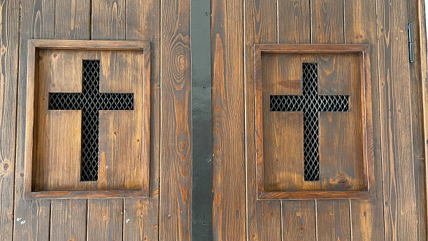 Confessional screen with two crosses cutout of metal mesh in a wooden church door