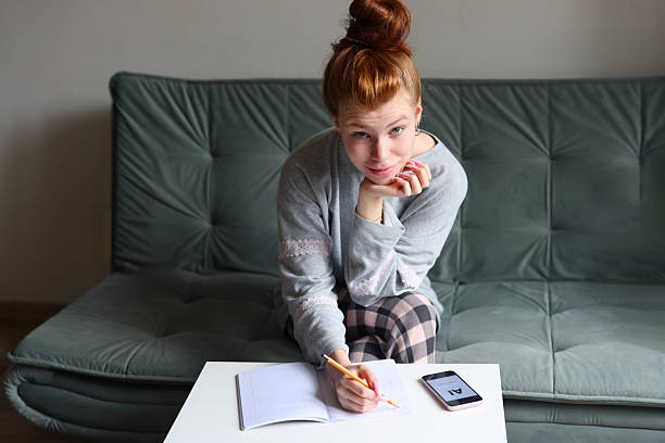 Woman learning online with AI app on smartphone and writing notes. High quality photo