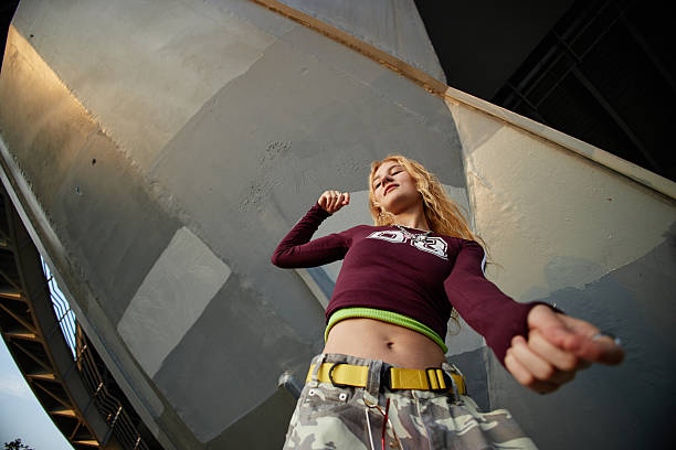 Caucasian girl dancing outdoors under urban structure, looking confident with expressive body language, wearing casual streetwear, representing Gen Z youth culture