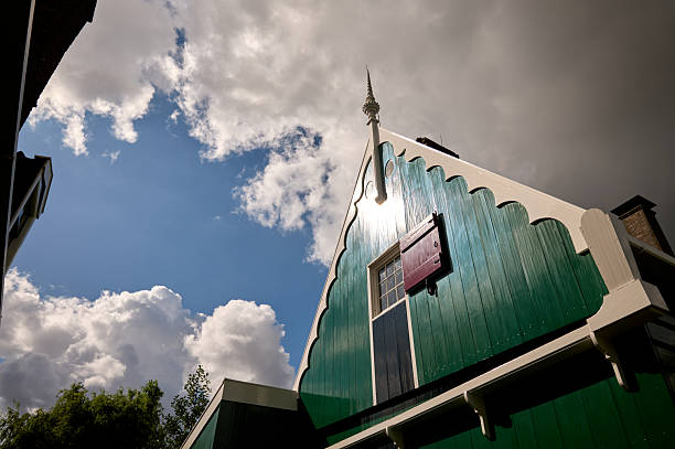 Traditional green wooden house gable under a dramatic sky with clouds in zaanse schans, netherlands