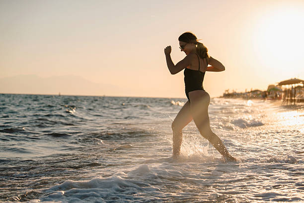 istock Woman running into the sea at sunset 2236415896