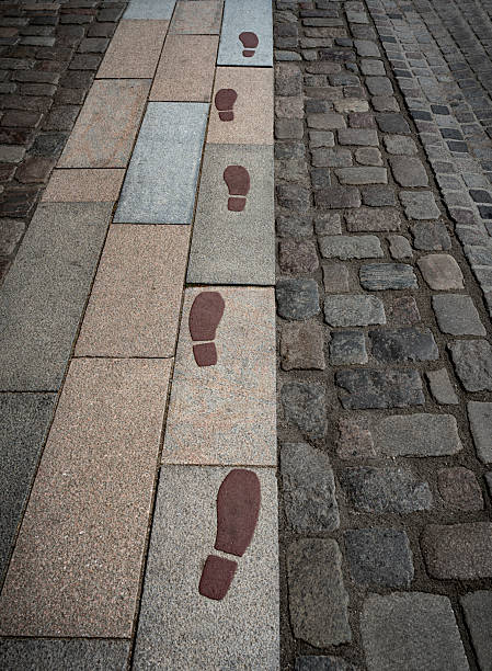 Red footprint signs on an asphalt road for pedestrian. Symbol of walkway.
