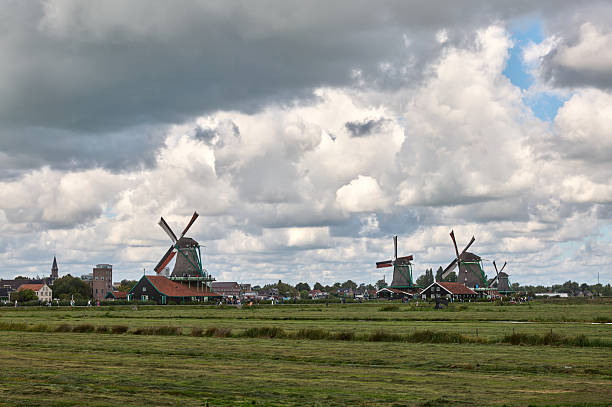 Historic windmills and traditional buildings dotting the dutch countryside under a cloudy sky