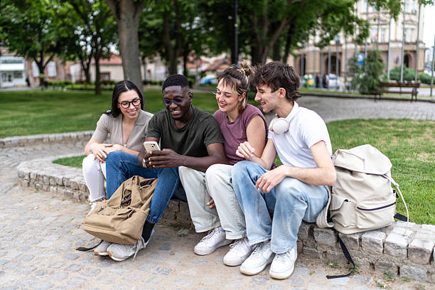 istock Diverse young adults sharing smartphone content in park 2236424872