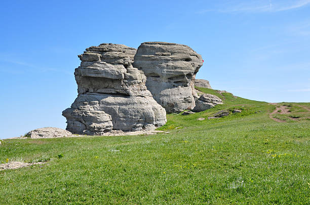 istock Unique Rock Formations Resembling Human Figures on a Green Hillside Under a Clear Blue Sky. 2236425149