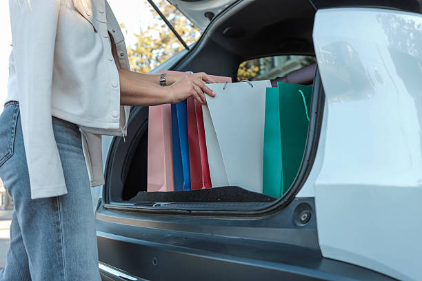 istock Woman loading shopping bags into car trunk 2236425340