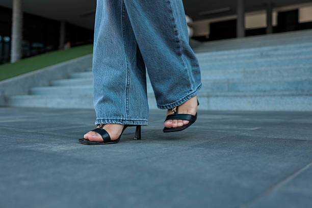 istock Woman's legs in denim jeans and black heels walking on a gray surface. 2236425360