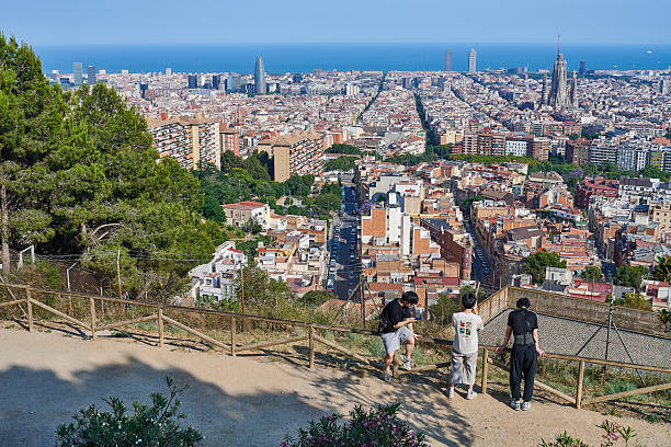 Barcelona, Spain - June 09, 2025: three Korean tourists enjoy a sunny afternoon overlooking Barcelona cityscape from the terrace of Bunkers del Carmel, a hill-side location in Horta-Guinardo district.
