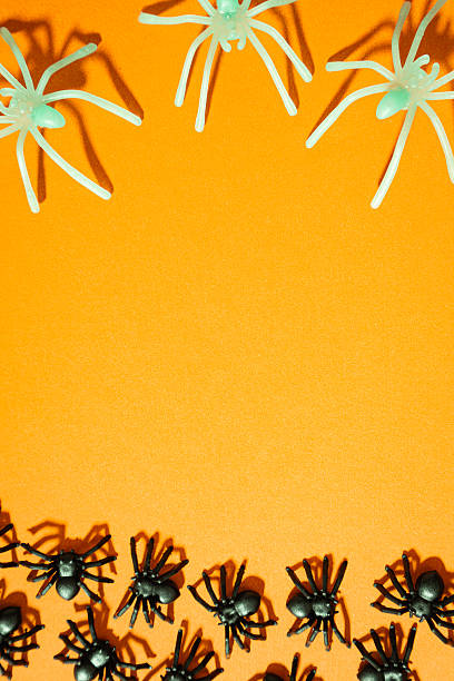 istock Fake spiders on an orange background. Halloween background 2236430366