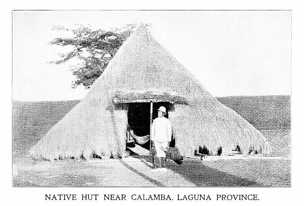 A British man stands in front of a grass hut on Calamba Island, Laguna Bay, Philippine Islands, an archipelago in the Pacific Ocean. Photograph engraving published 1898. Copyright expired; artwork is in Public Domain.