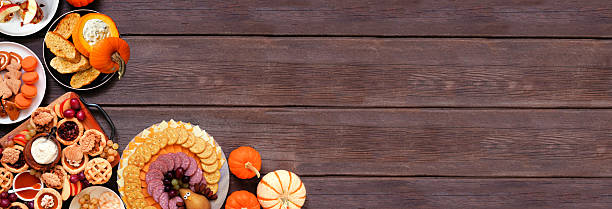 istock Thanksgiving appetizers, sweets and grazing boards. Overhead view corner border on a dark wood banner background. 2236438111