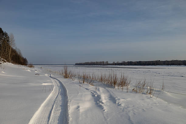 Snowmobile track marks on the snow of frozen river