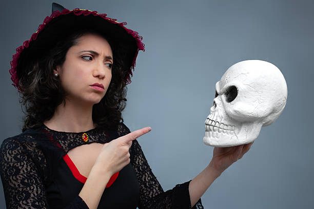 istock Upset witch scolding a skull, pointing a finger at it. 2236448240