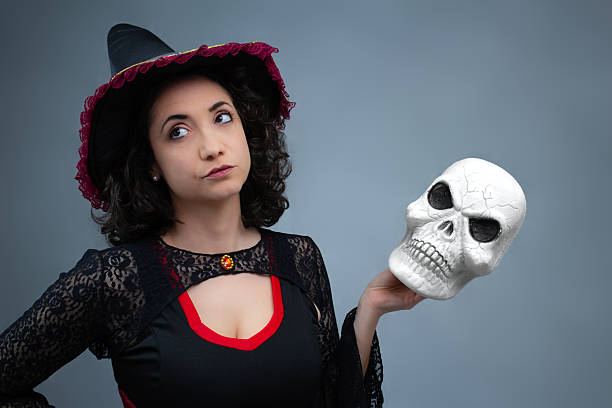 istock Funny witch rolling her eyes, annoyed, holding a spooky skull in her hand. 2236448242