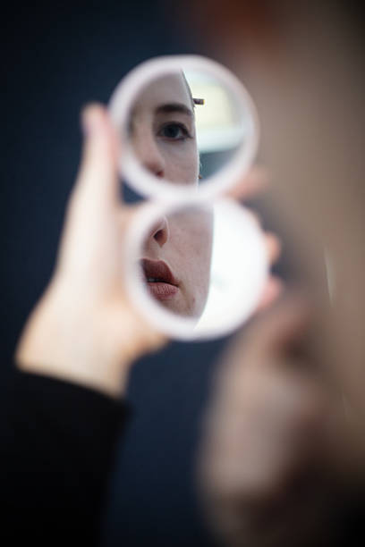 Stylish woman wearing a sleek black dress  putting on a smart AI necklace in front of the mirror