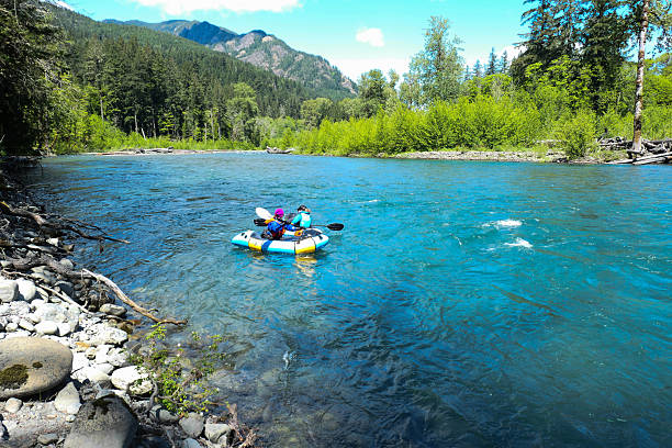 Two people in a pair of rafts getting ready to float down the Elwha River, in the Olympic National Park in Washington state.  Sunny day and clear water.