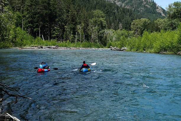 Two people in a pair of rafts beginning to float down the Elwha River, in the Olympic National Park in Washington state.  Sunny day and clear water.
