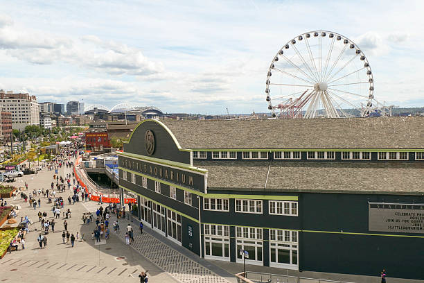 Downtown view of the waterfront in Seattle, WA.  The Ferris wheel and Aquarium are the main structures in this pictures.  Lots of people walking along the waterfront.
