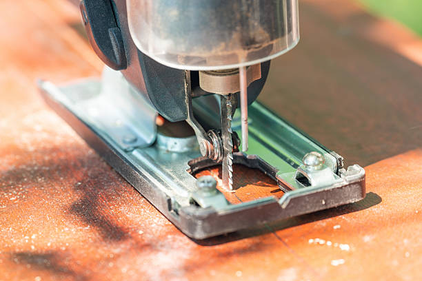 A carpenter cuts a board with an electric jigsaw.