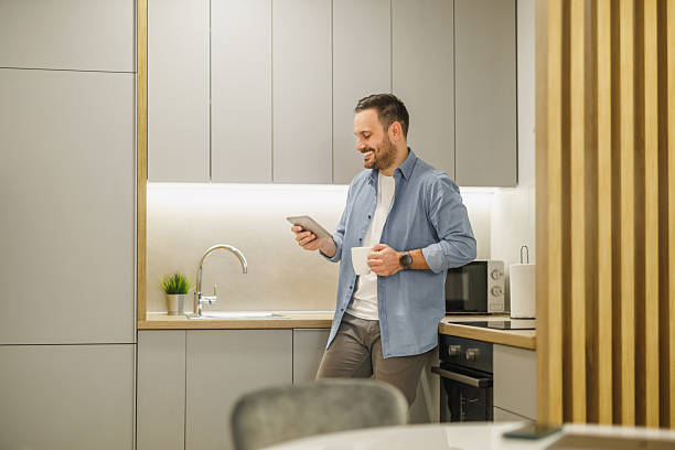 istock Man enjoying coffee while reading on his tablet in a modern kitchen during the morning 2236453133