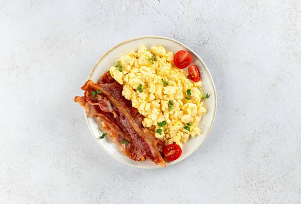 istock Scrambled eggs with crispy bacon and tomatoes on a white background. Classic breakfast. 2236471759