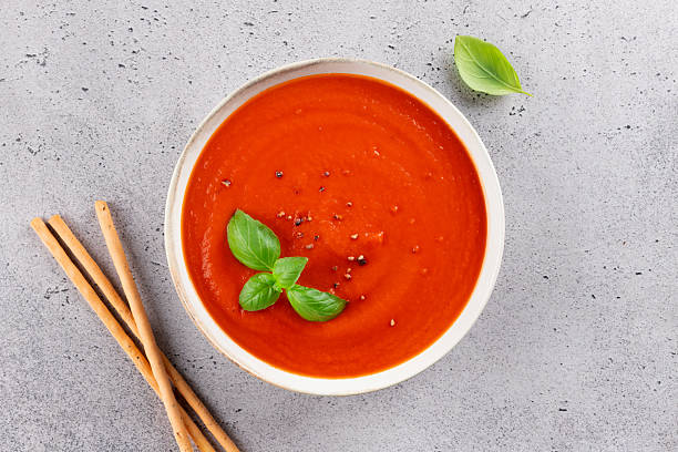 istock Tomato cream soup with fresh basil and breadsticks on a light stone background. Top view. Healthy vegetarian meal. 2236471834