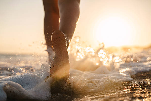istock Woman splashing waves while running on the beach at sunset 2236471985